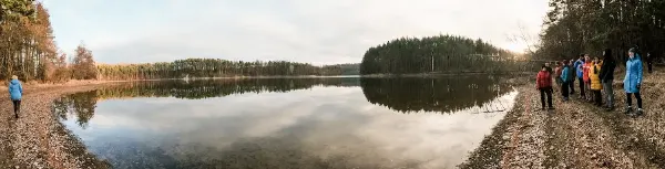 Skupina lidí na hudební dovolené u jezera u lesa.
