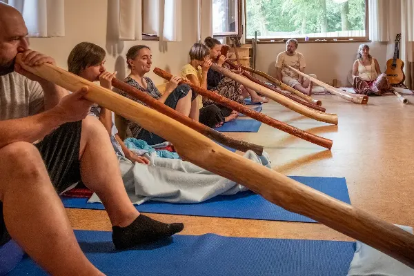 Skupina lidí hrající didgeridoo v centru zvukové terapie Dajána.