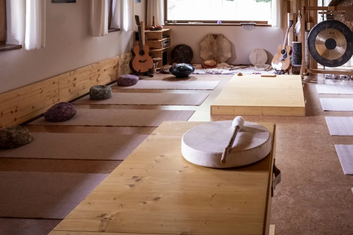 Místnost pro zvukovou terapii se meditačními gongy, tibetskými mísami, kytarou a hudebními nástroji na stěnách.