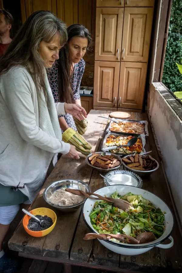 Dvě ženy připravují jídlo v kuchyni - vidět salát, maso a různé ingredience.