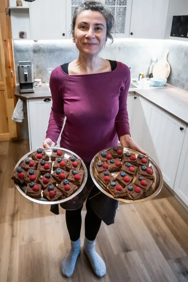Žena v kuchyni s talířem domácího čokoládového dezertu.