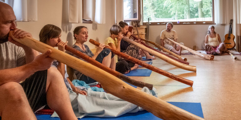 Účastníci semináře hrají na didgeridoo v centru Dajána
